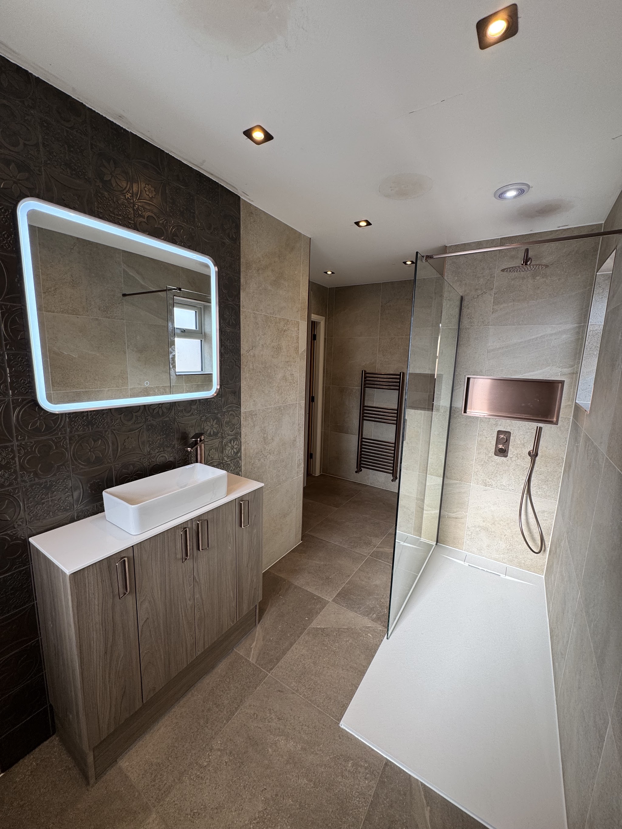 Finished shower room by Linden Whitehead: walk-in shower, backlit mirror and vessel basin on a grey vanity