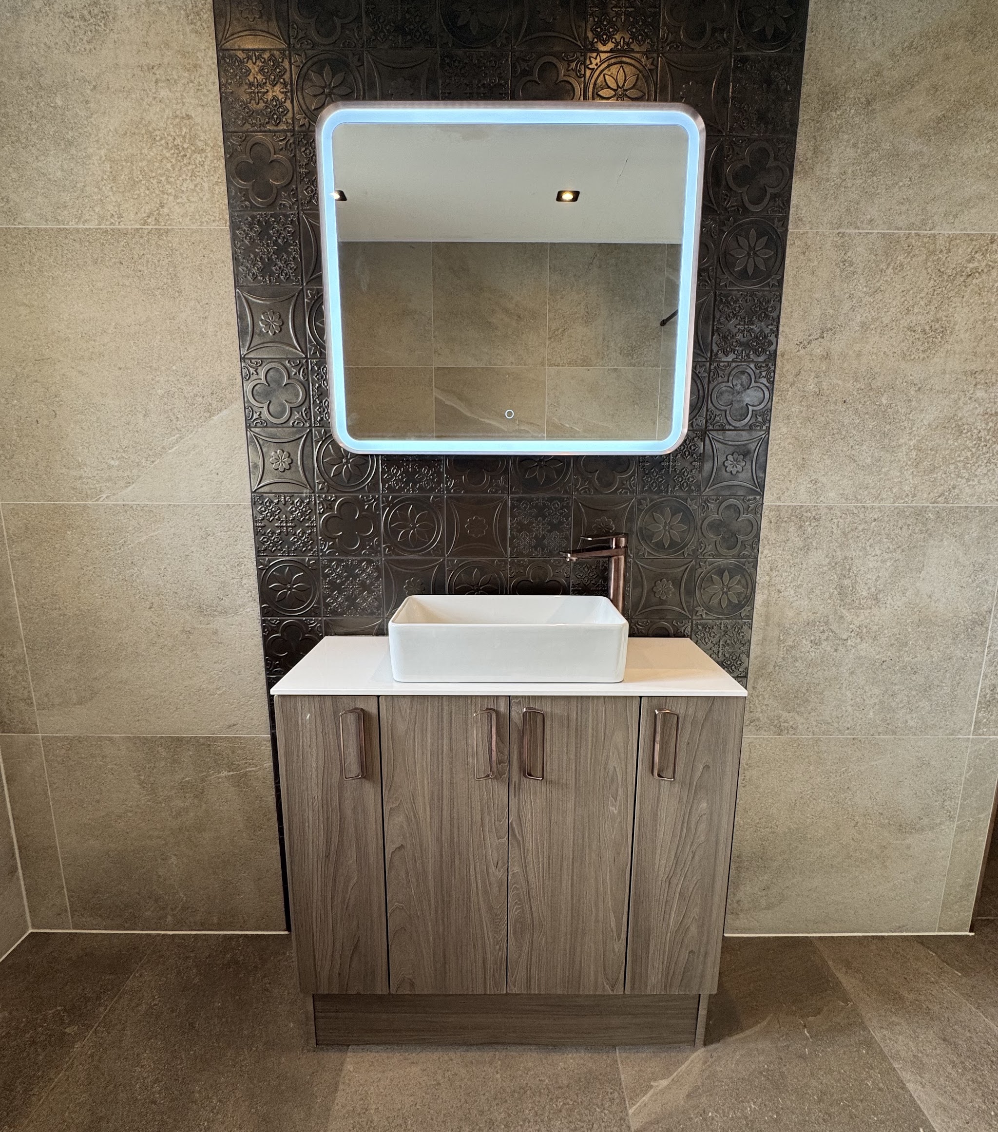 Rectangular basin on a wood-effect vanity beneath a backlit mirror and patterned dark feature wall