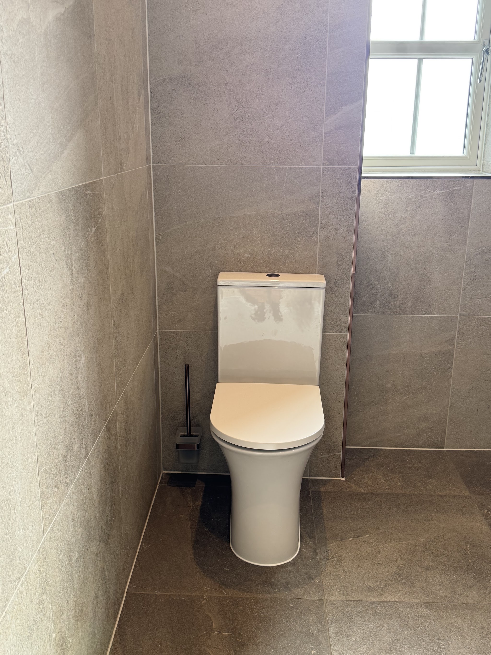Close-coupled toilet set against large-format grey stone tiles